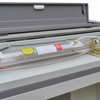 Стеклянная лазерная трубка Reci с подключенными трубками охлаждения зафиксирована в держателях внутри заднего отсека металлического корпуса
